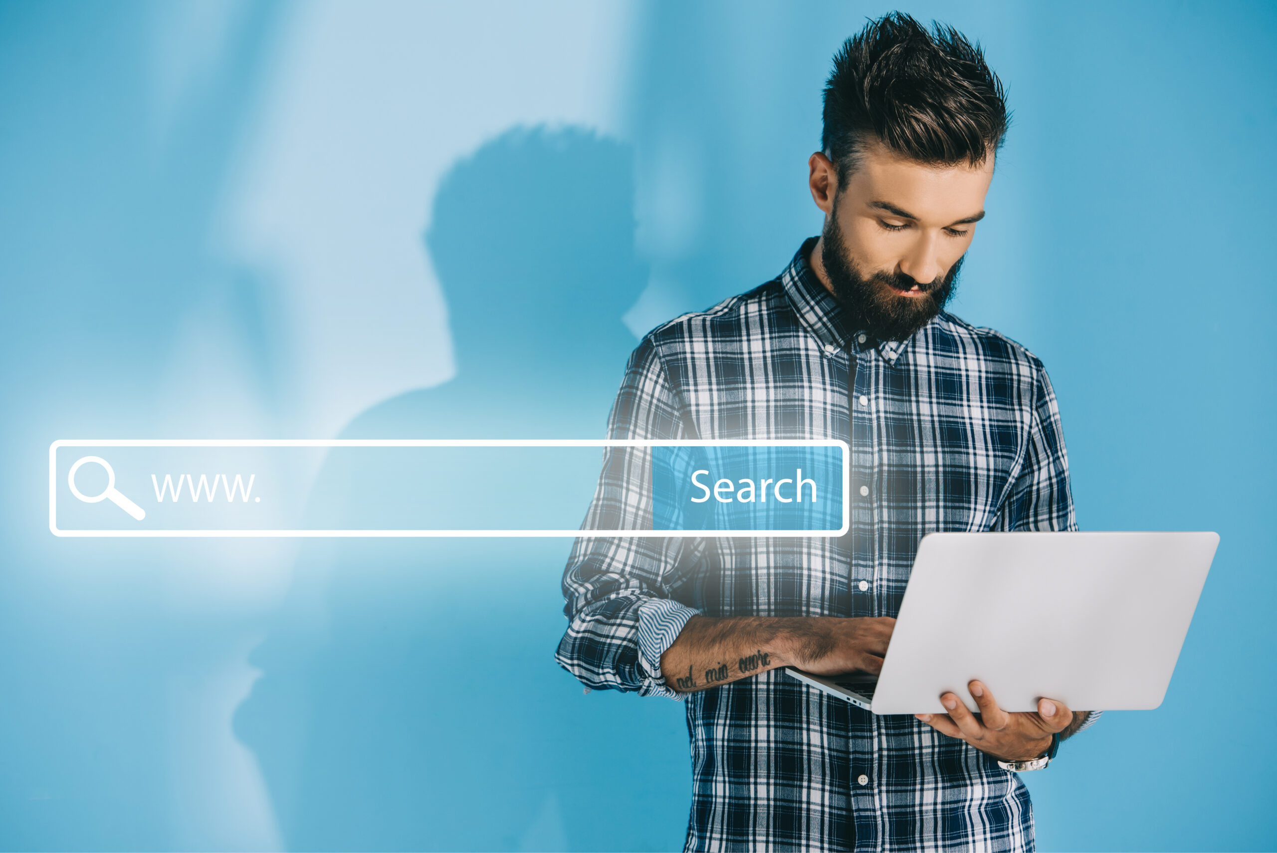 bearded developer using laptop, on blue with website search bar kenya business solution model